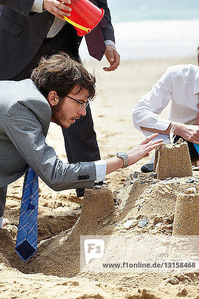 Geschäftsleute bauen eine Sandburg