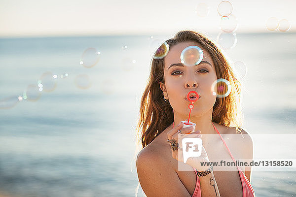 Porträt einer jungen Frau am Strand  die Seifenblasen bläst  Castiadas  Sardinien  Italien