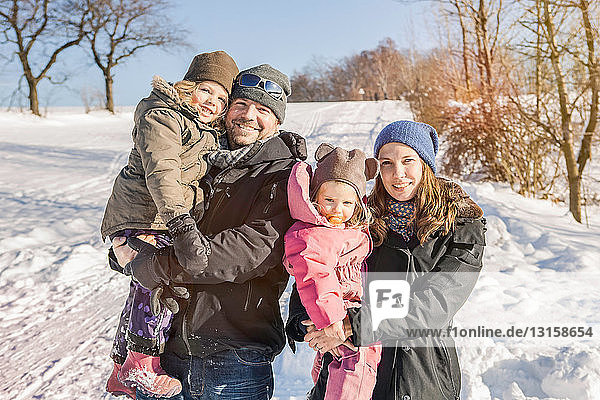 Familie lächelt gemeinsam im Schnee