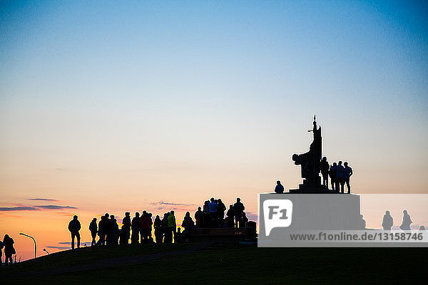 Silhouette einer Menschenmenge um ein Denkmal bei Sonnenuntergang  Reykjavik  Island