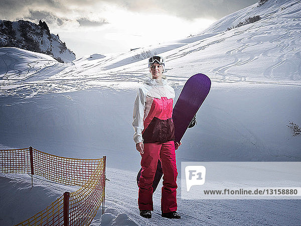 Frau mit Snowboard auf verschneiter Piste