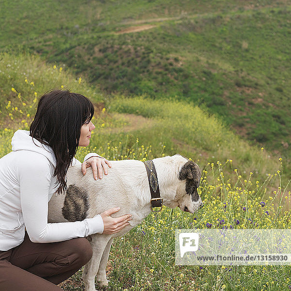 Frau umarmt Hund auf Naturlehrpfad