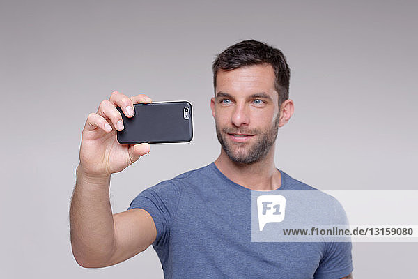 Mittelgroßer erwachsener Mann  fotografierend  mit Smartphone