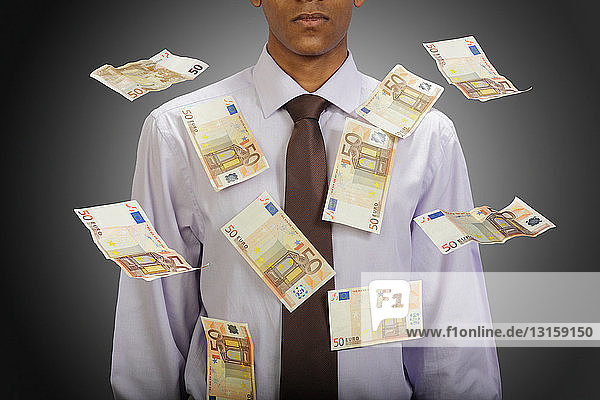 Euro-Banknoten fliegen um Geschäftsmann