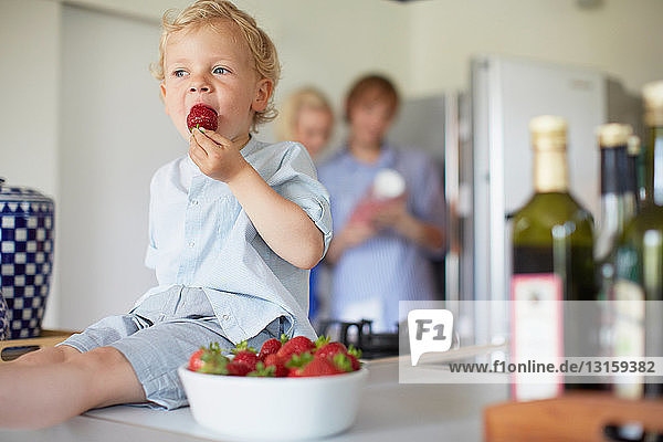 Boy eating strawberries on counter