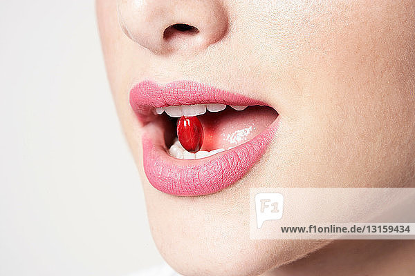 Frau mit Pille zwischen den Zähnen