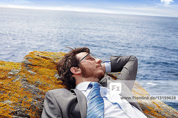 Businessman relaxing on cliff
