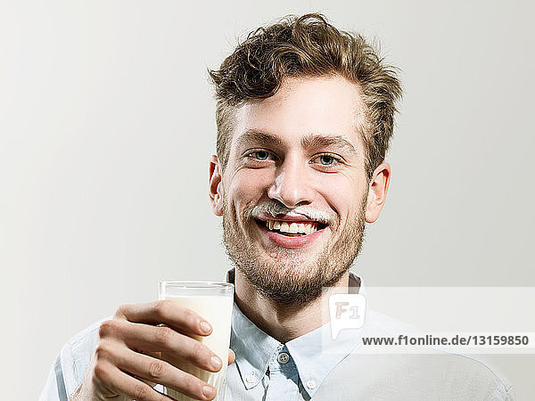 Young man smiling with milk moustache  studio shot