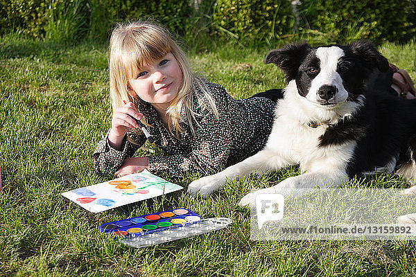 Child paint with her dog in the garden