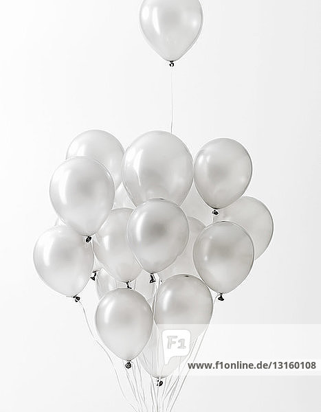 Silver balloons floating against white background