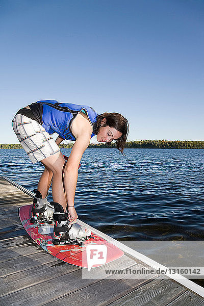 Frau beim Anschnallen auf dem Wakeboard