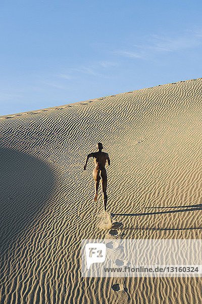 Nackte Frau läuft in der Wüste und hinterlässt Fußspuren