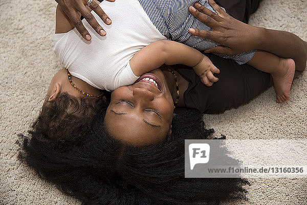 Mid erwachsene Frau umarmt Kleinkind Tochter auf Teppich