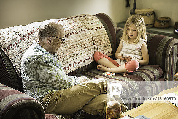 Großvater und Enkelin spielen Karten auf dem Sofa