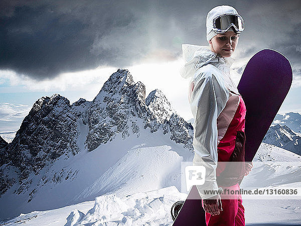 Woman with snowboard on snowy mountain