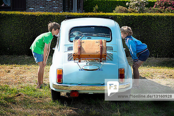 Boys looking through windows of vintage automobile