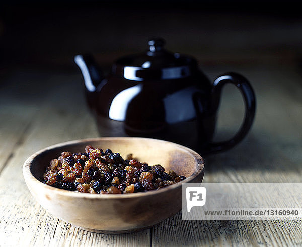 Still life of raisins in bowl and pot of tea