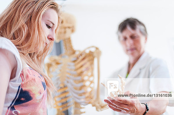 Frau zeigt Teenager-Mittelhandknochen auf anatomischem Modell