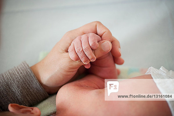 Mutter hält die Hand ihres neugeborenen Babys
