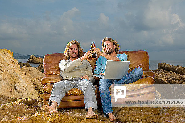 junge Männer mit Laptop und Bier  Couch bei