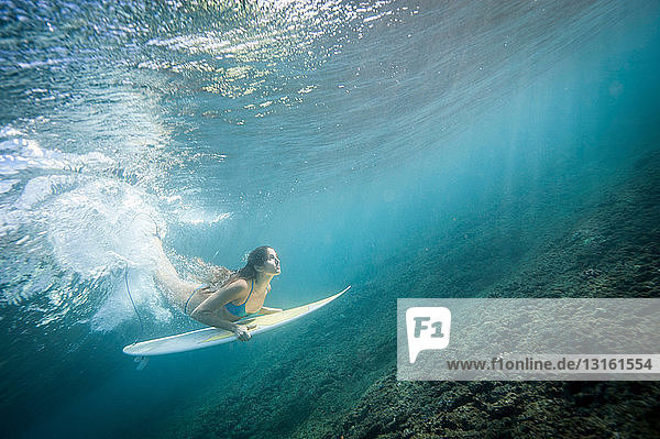 Surfer diving under wave in water