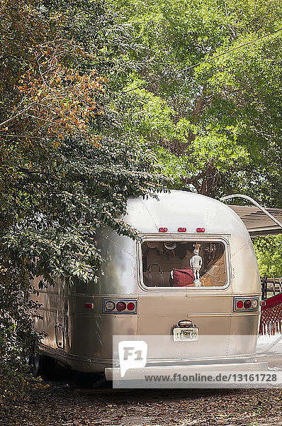 Rear view of parked airstream trailer with statue in window