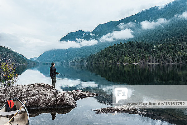 Man fishing from rocks  Buntzen Lake  British Columbia  Canada