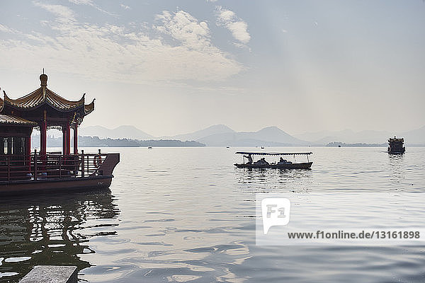 Blick auf die Silhouette eines Fischerbootes und eines Seerestaurants am Westlake  Hangzhou  China