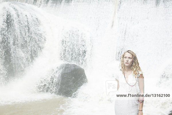 Teenager-Mädchen steht am Wasserfall