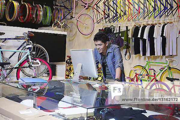 Junger Mann im Fahrradladen mit Computer