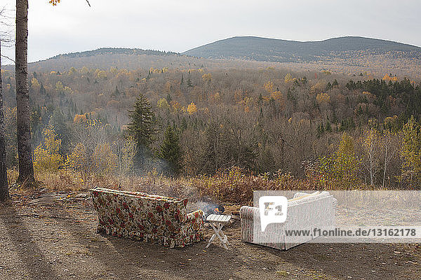 Two sofas and campfire with autumn forest view  Maine  USA