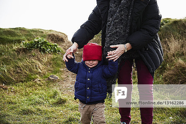 Männliches Kleinkind und Mutter halten sich beim Gehen in der Düne an den Händen