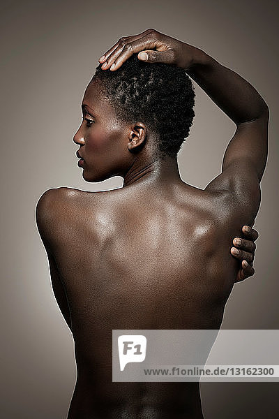 Rückenansicht einer nackten Frau mit Hand auf dem Kopf