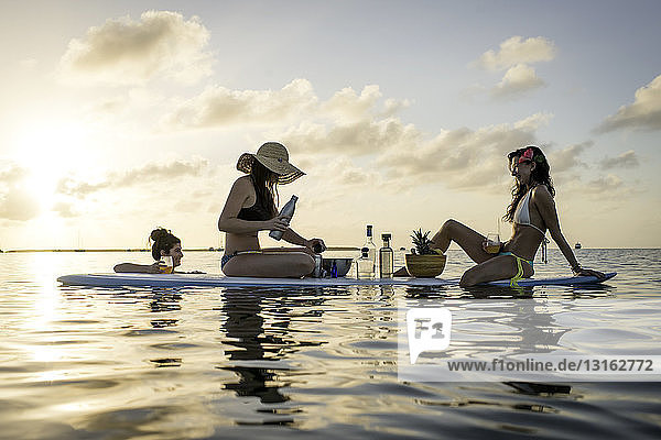 Two young women preparing cocktails on paddleboard at sunset  Islamorada  Florida  USA