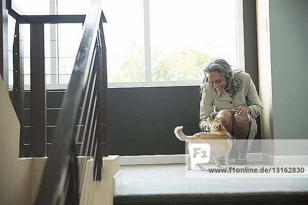 Reife Frau streichelt ihren Hund auf der Treppe