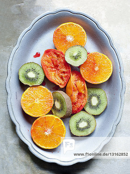Gericht mit in Scheiben geschnittener Kiwi und Orangenfrucht und gepresster Blutorange