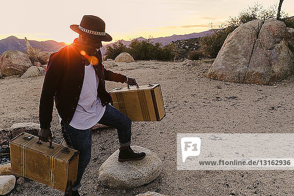 Mid adult man unloading road trip suitcases at sunset  Los Angeles  California  USA