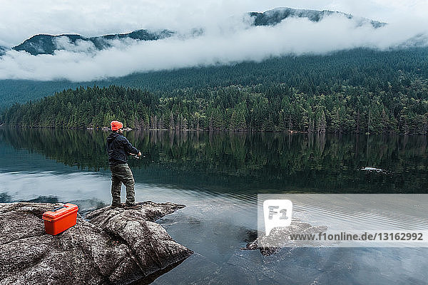 Man fishing from rocks  Buntzen Lake  British Columbia  Canada