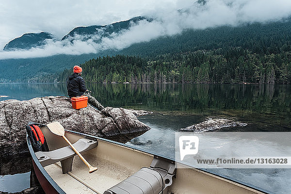 Man fishing from rocks,  Buntzen Lake,  British Columbia,  Canada