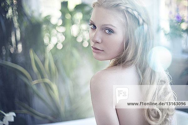 Nackte junge Frau  blonde Haare  über die Schulter schauend