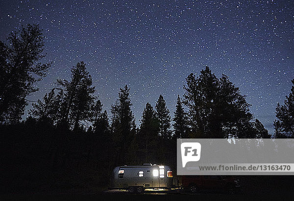 Camping trailer and silhouetted trees at night  Diamond Lake  Oregon  USA