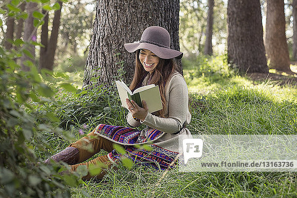 Young woman reading book in forest