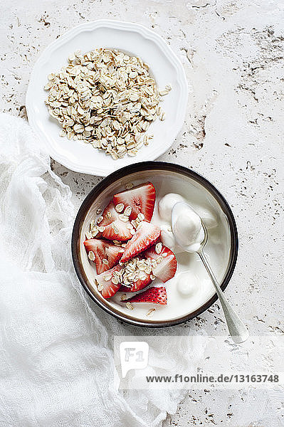 Stilleben von Joghurtschalen mit in Scheiben geschnittener Erdbeere und Hafer