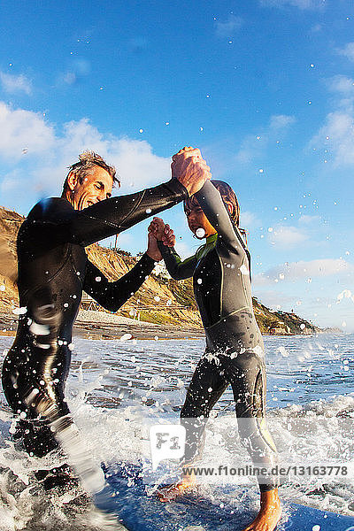 Father and daughter jumping in sea  Encinitas  California  USA