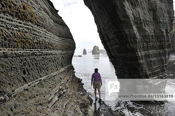 Junge Frau erkundet Strandfelsformation  Nordinsel  Neuseeland