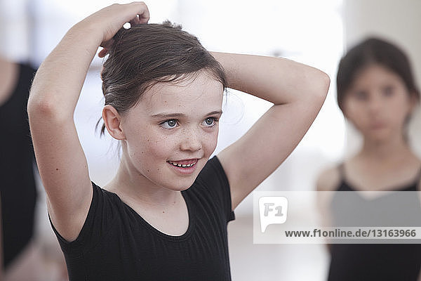 Girl pinning back her hair in ballet school
