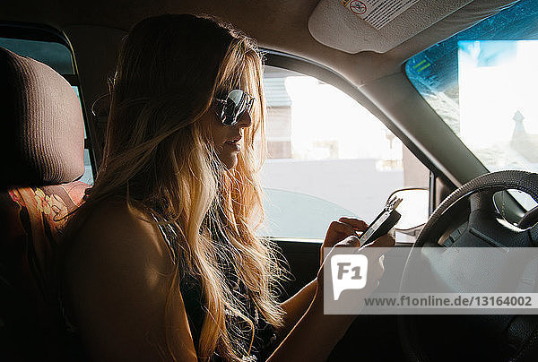 Junge Frau benutzt Mobiltelefon im Auto