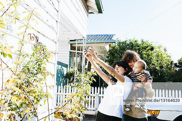 Frau nimmt Familien-Selfie vor dem Haus