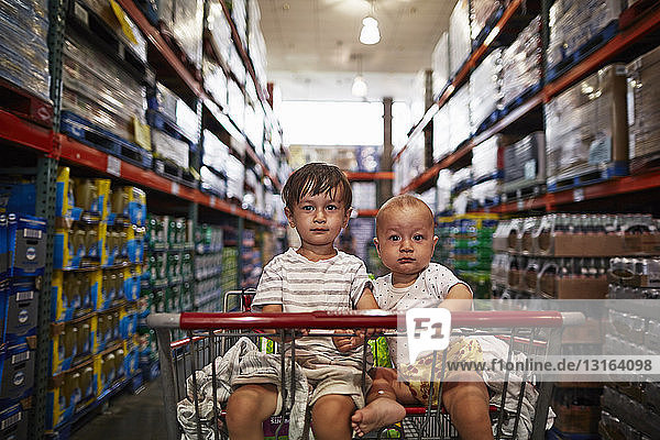 Brüder sitzen im Einkaufswagen