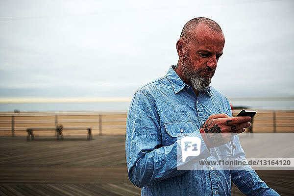Mann benutzt Smartphone am Meer